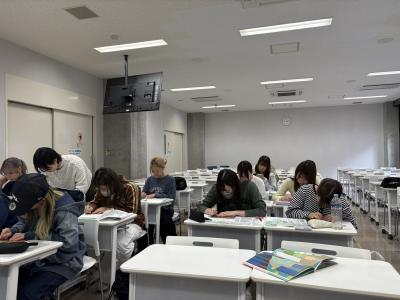 点字を一文字ずつ確認しながら、絵本に貼り付ける学生たち